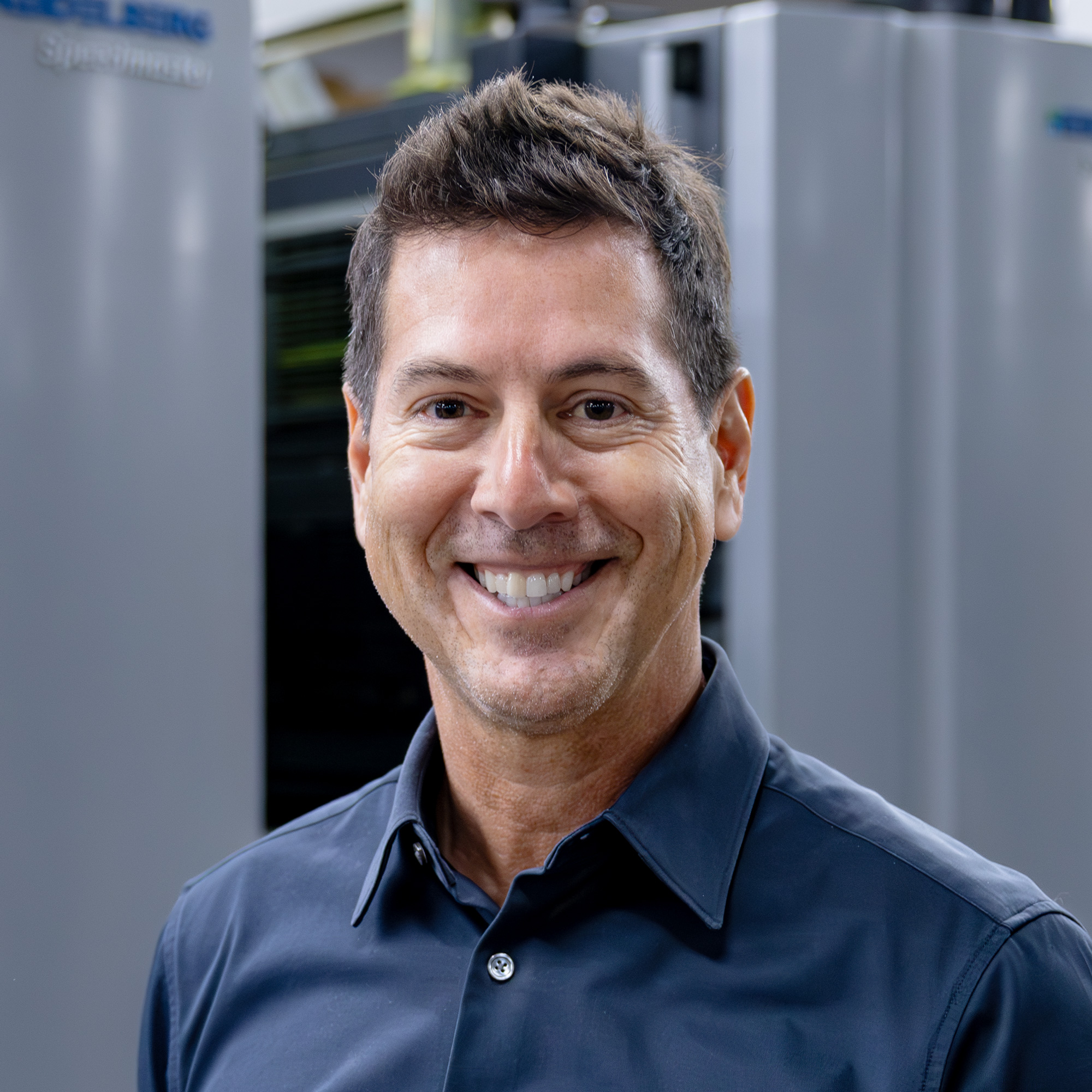 Simon smiling in front of a printer