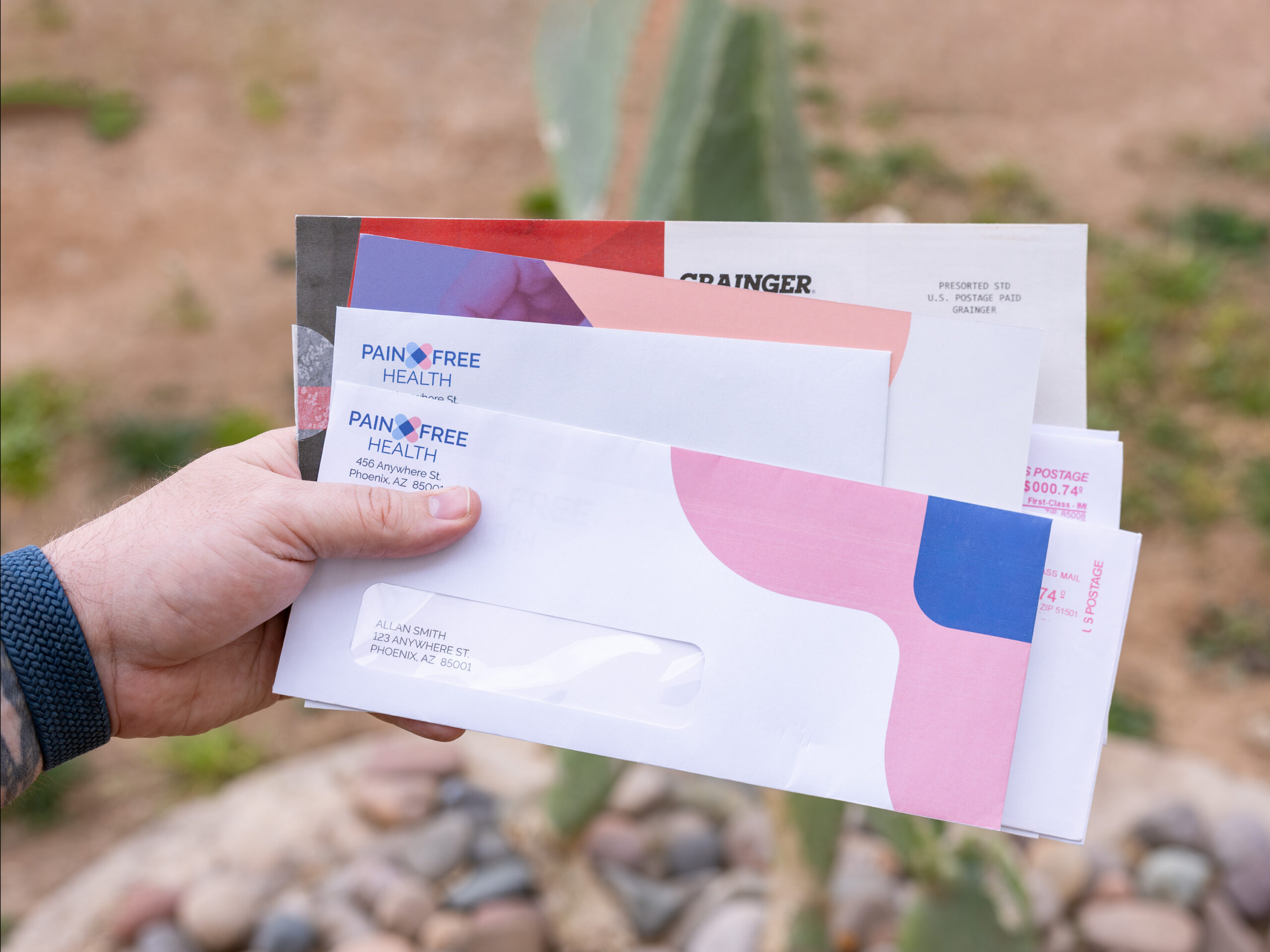 Person holding a stack of Pain Free Health mailers outside