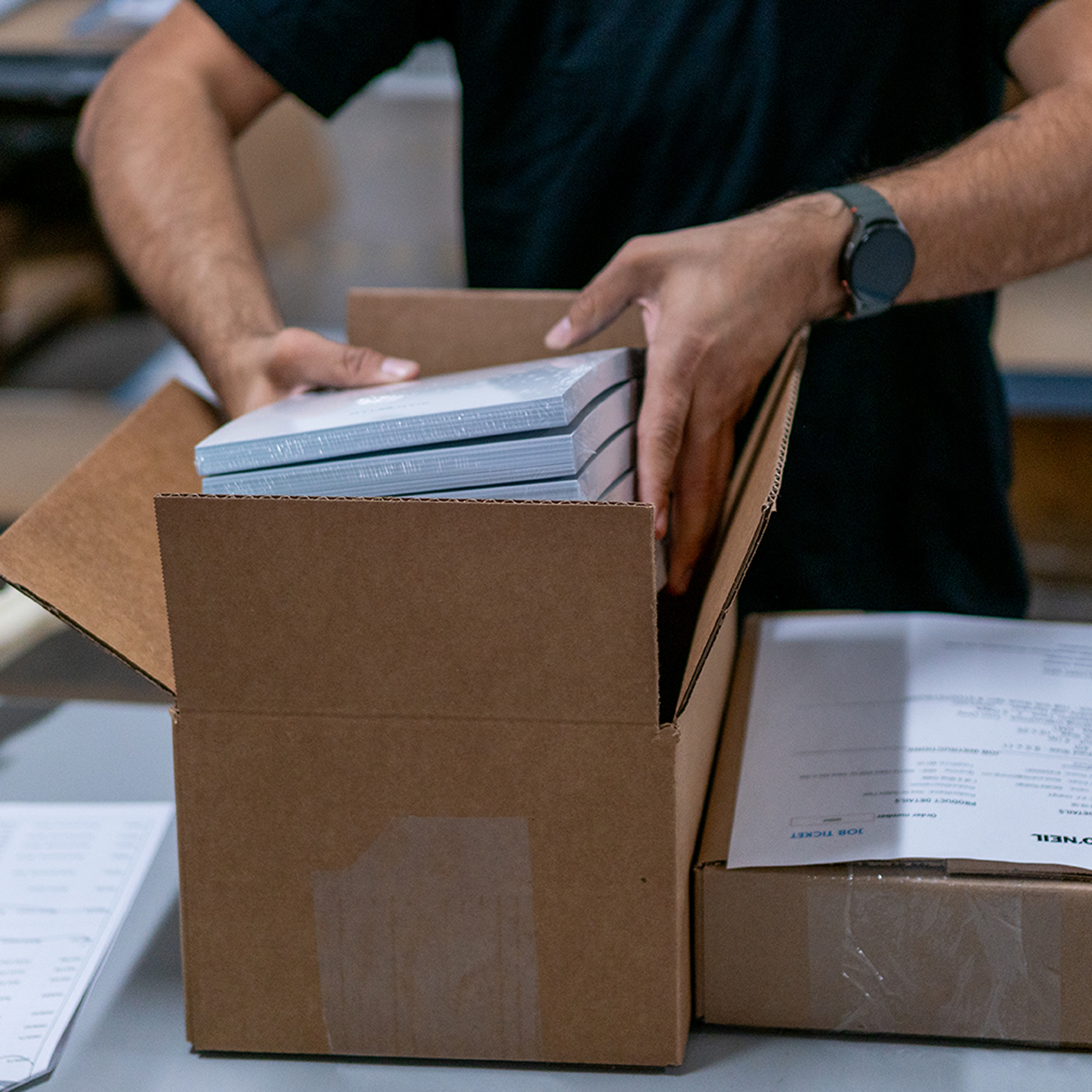 O'Neil team member placing shrinkwrapped packs into a box