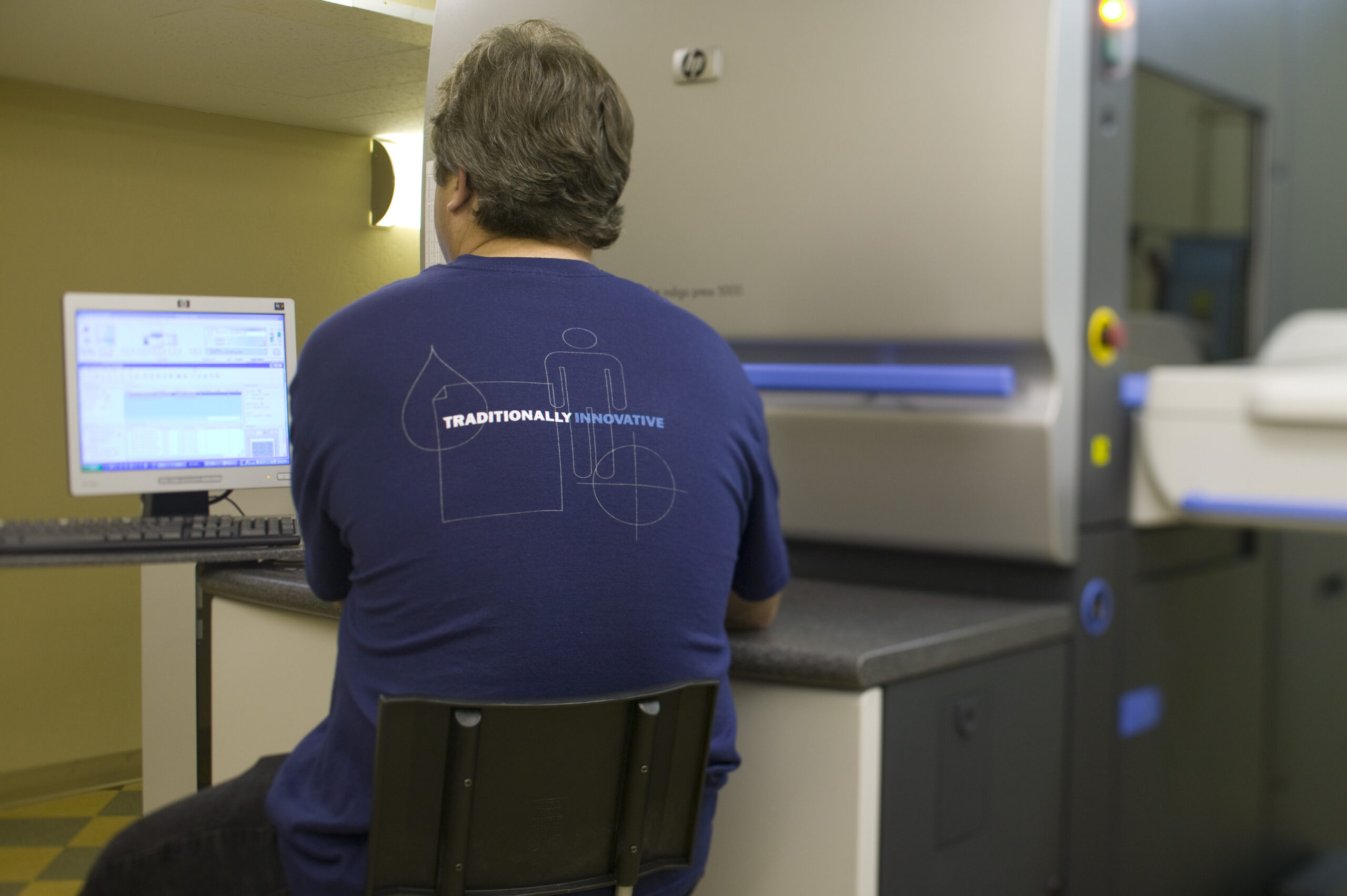 O'Neil employee shot from behind working at a a computer for the digital press