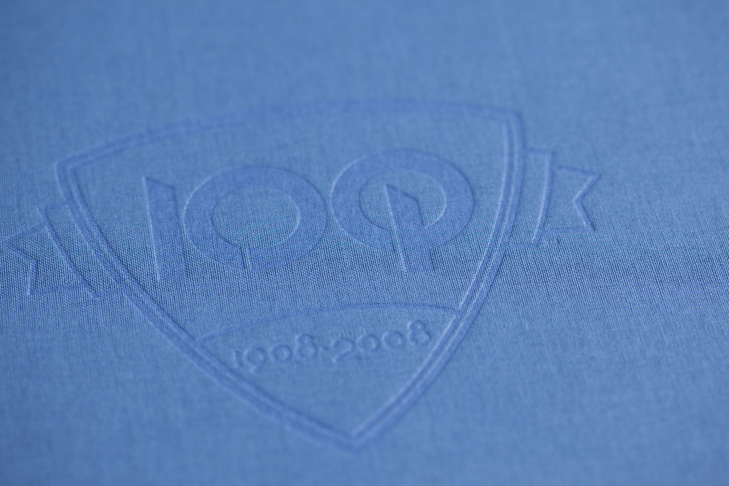 Blue fabric book cover with embossed O'Neil 100th Anniversary logo