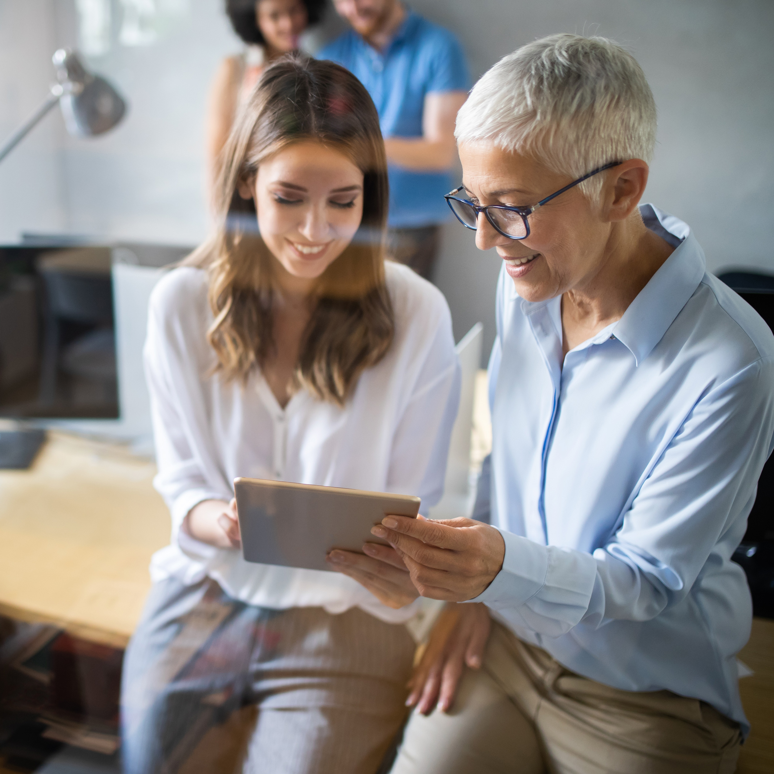 Two female creative marketing managers looking down at a tablet in an office