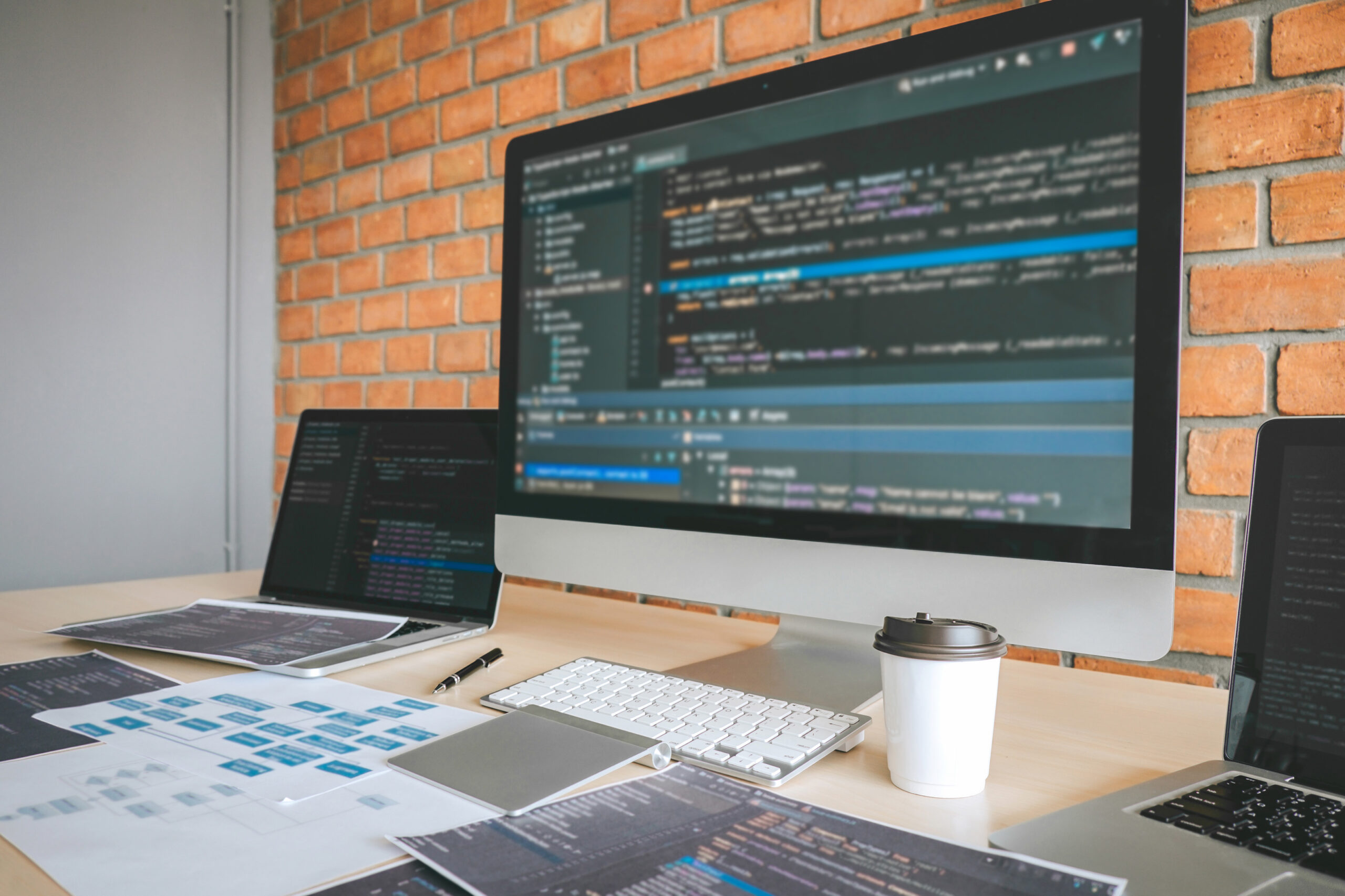 Professional developer's desk with multiple computers showing code