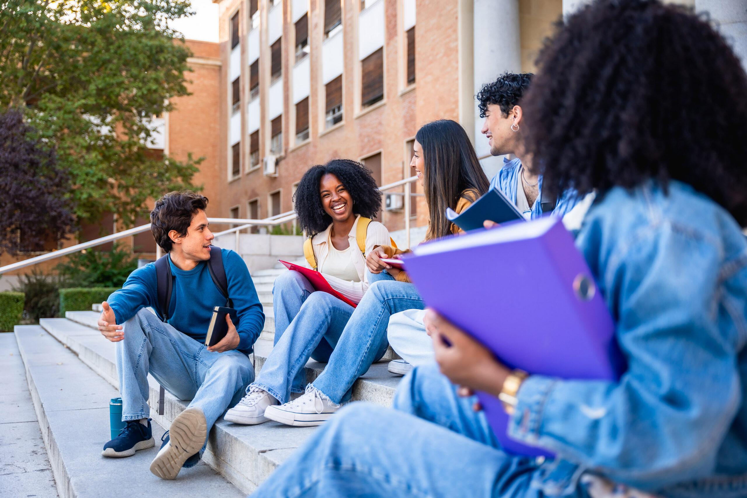 Group of college students in conversation on campus steps