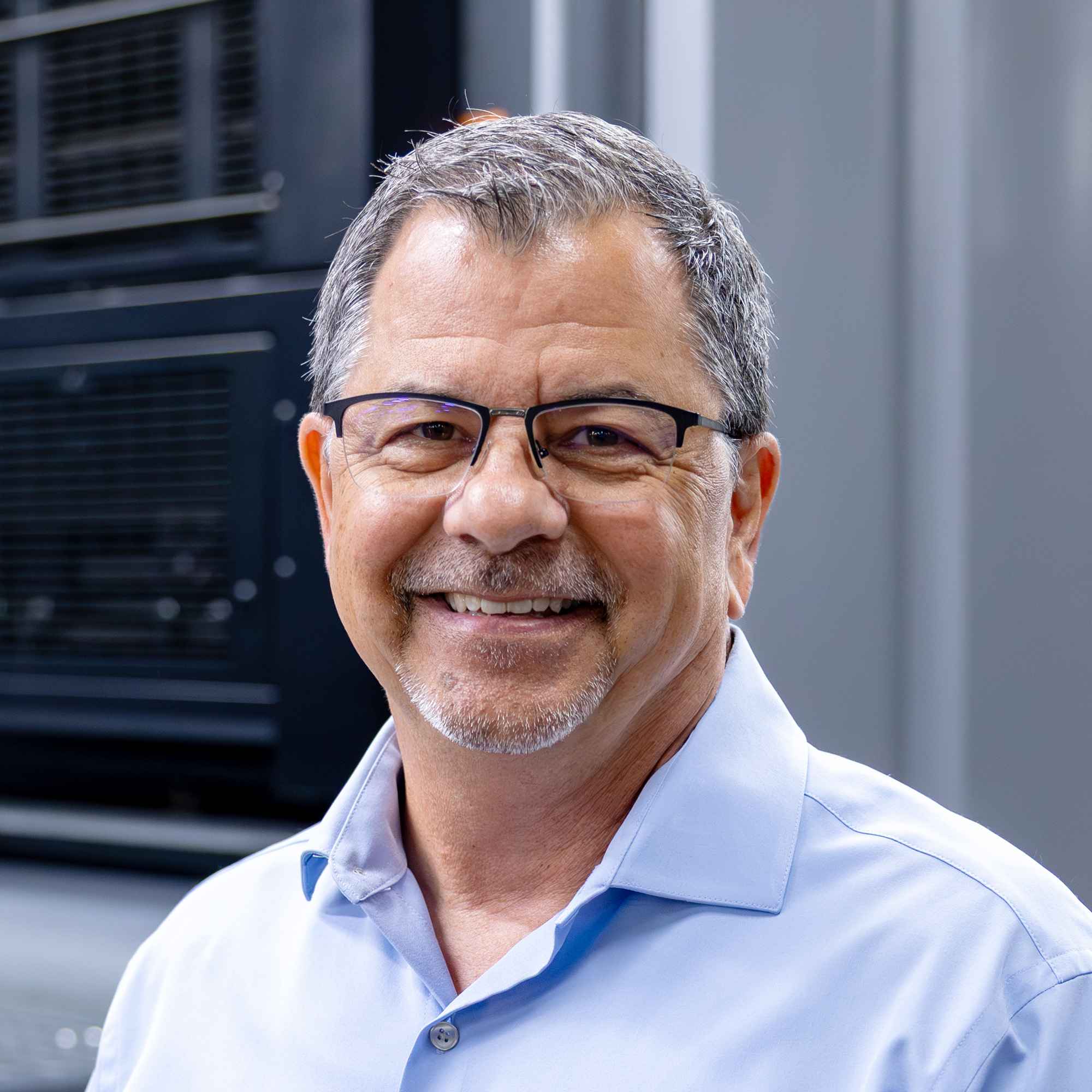 Dean smiling in front of a printer