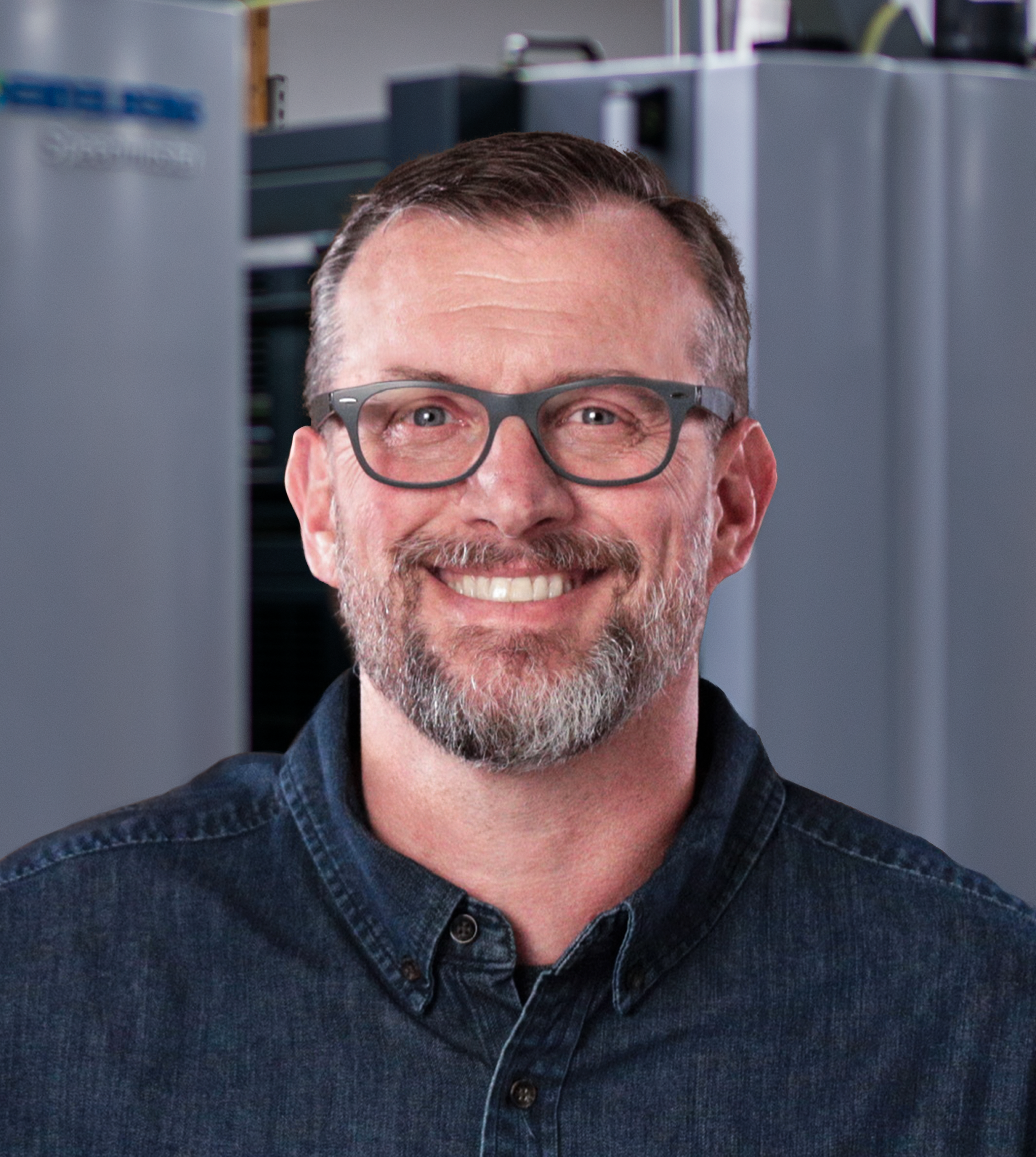 Justin smiling in front of a printer